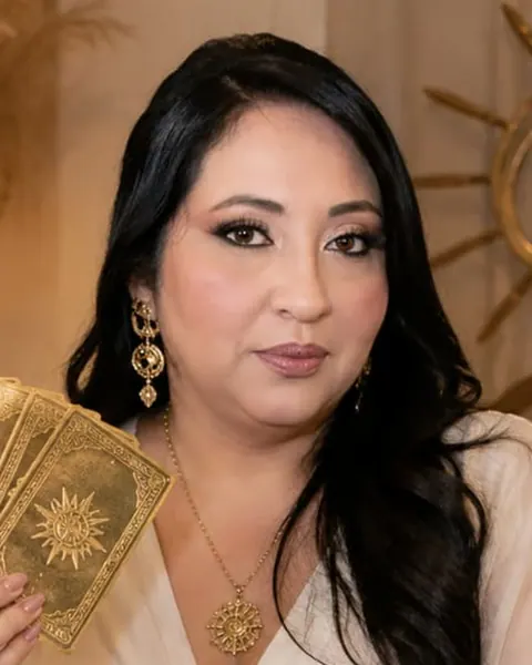 Vanessa, a Taróloga da Luz, de branco, com as cartas na mão